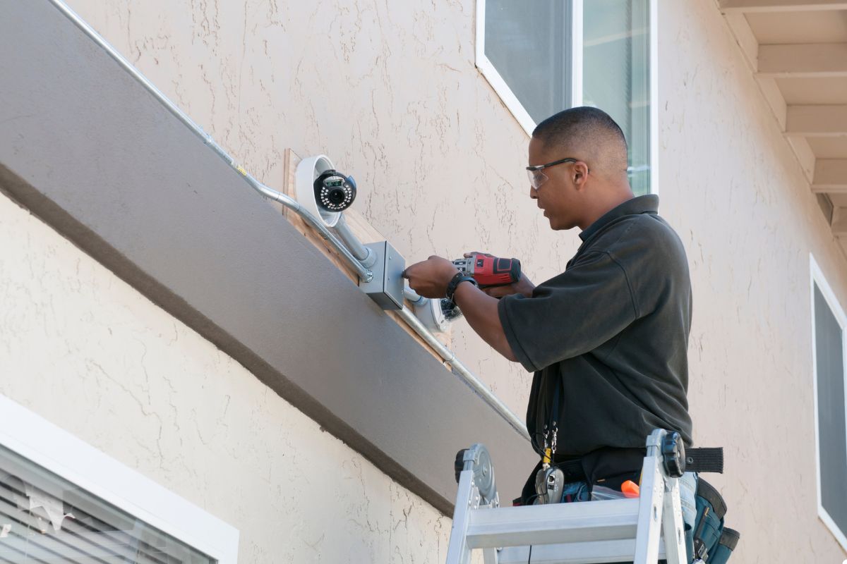 A man using a ladder to fix a window, demonstrating his commitment to home improvement and safety. 