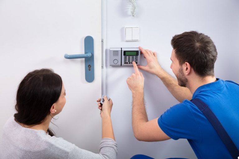 A man and woman collaborate to repair a door lock, focused on their task with tools in hand.